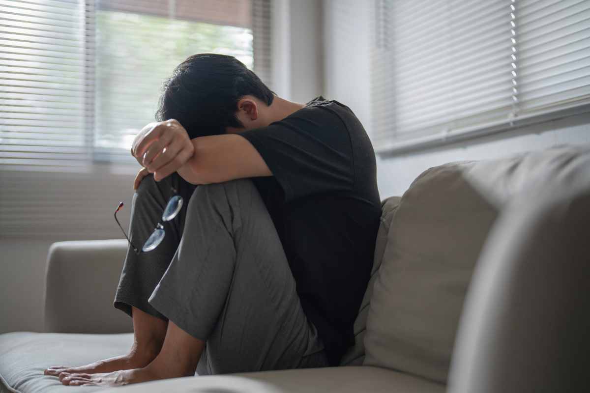un giovane con la testa tra le braccia su un divano