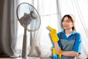 Donna con guanti, grembiule e prodotto spray, indica ventilatore