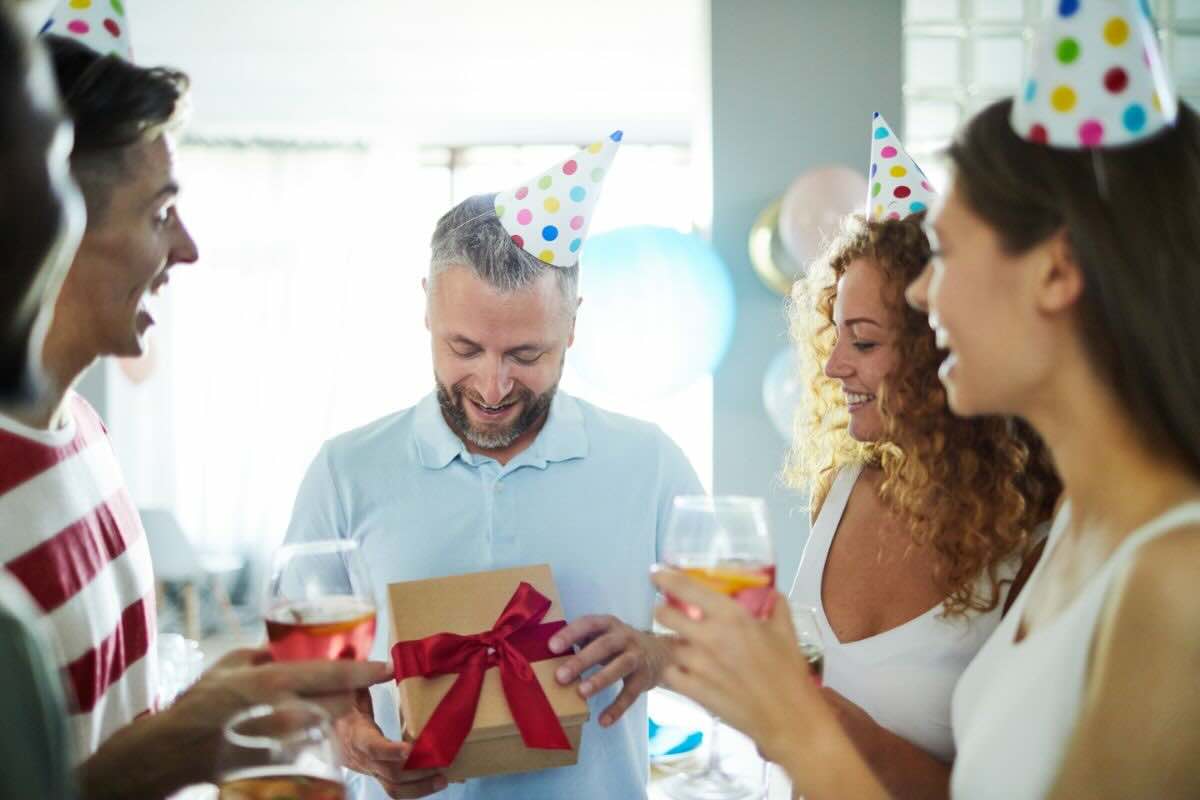 jene-stephaniuk-lkmGeyLItrw-unsplash-ls Uomo con regalo in mano e altri amici che lo festeggiano